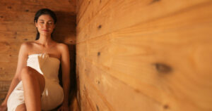 young woman in towel relaxing in wooden sauna at s 2024 01 31 18 21 01 utc 1024x540 1